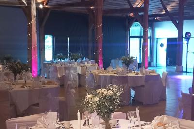 Espace d'attente avec fauteuils noirs, tables basses, escalier en bois courbé et plantes dans un intérieur lumineux.