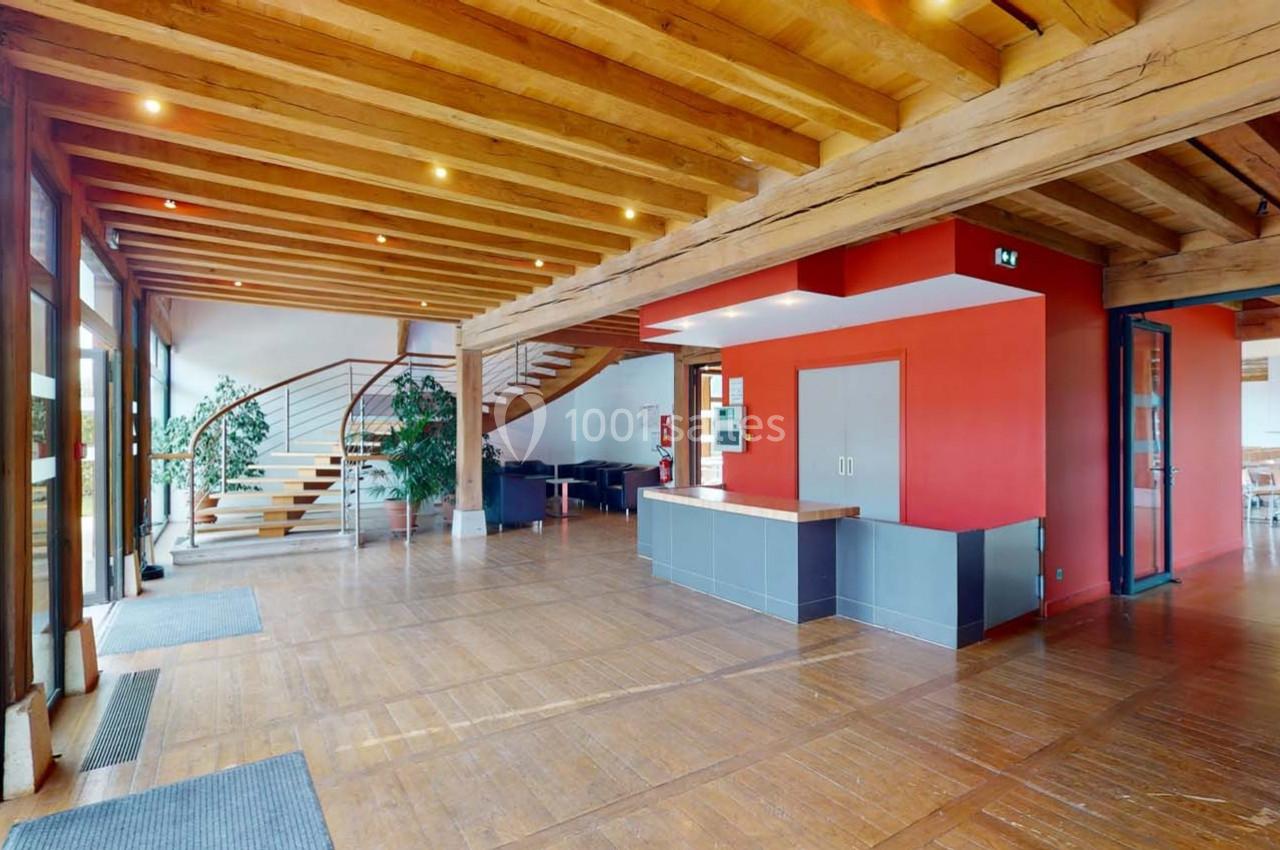 Intérieur d'un espace lumineux avec plafond en bois, escalier moderne, murs rouges et grandes fenêtres vitrées.