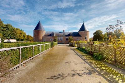 Espace d'attente avec fauteuils noirs, tables basses, escalier en bois courbé et plantes dans un intérieur lumineux.