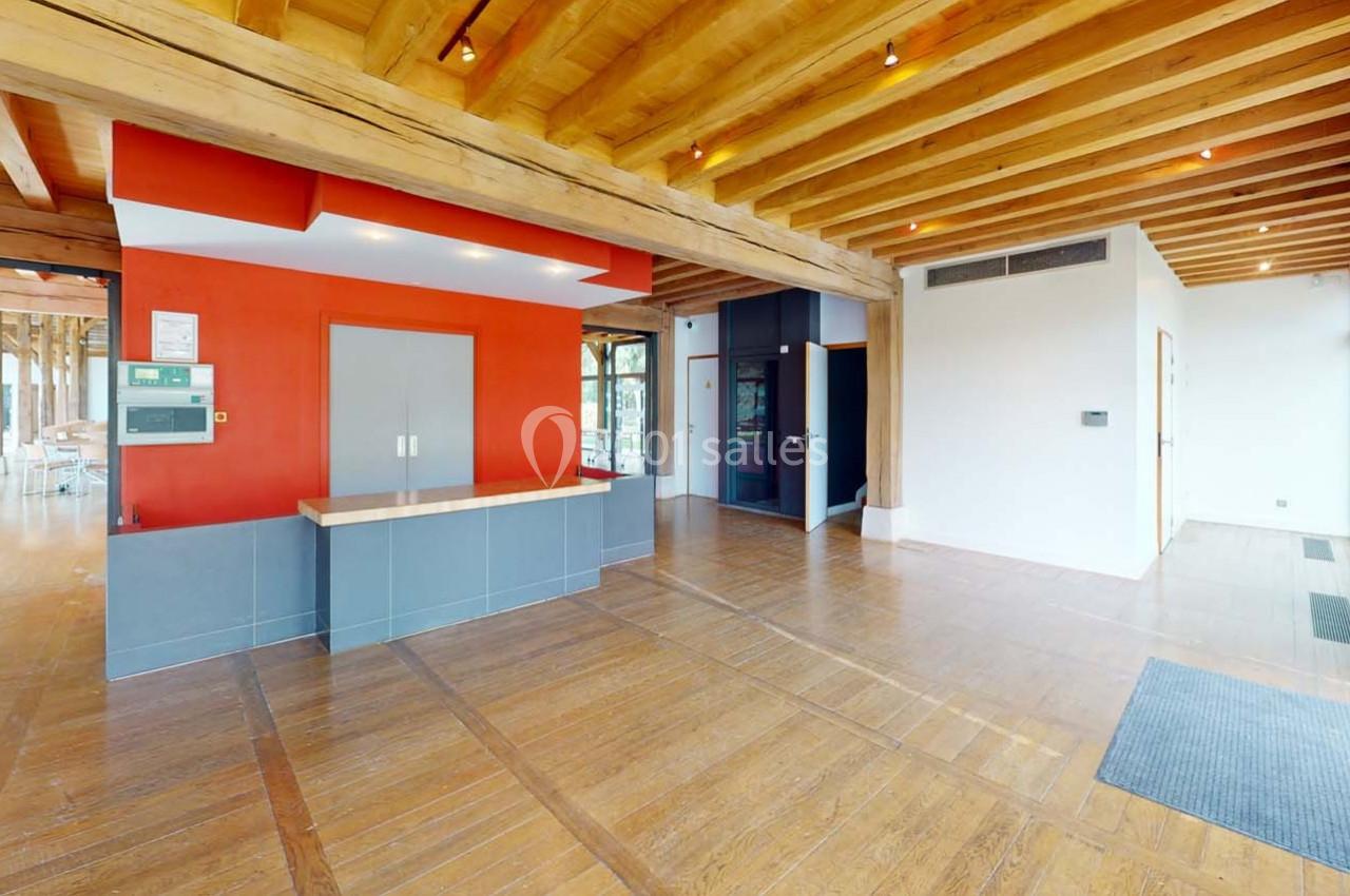 Intérieur d'un espace avec plafond en bois, murs blancs et rouges, sol en parquet et comptoir moderne.