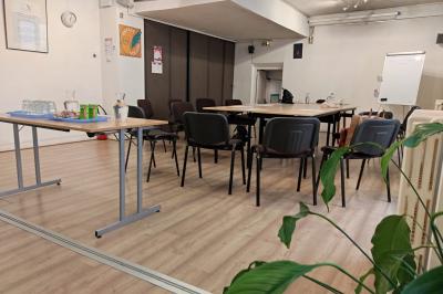 Salle de réunion lumineuse avec une grande table rectangulaire, des chaises noires et des fenêtres donnant sur l'extérieur.