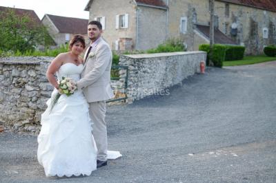 Un couple en tenue de mariage pose sur des rails entourés de verdure dans un cadre naturel et lumineux.