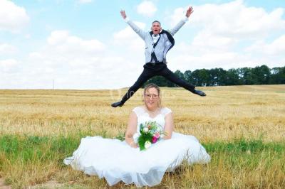 Un couple en tenue de mariage pose sur des rails entourés de verdure dans un cadre naturel et lumineux.