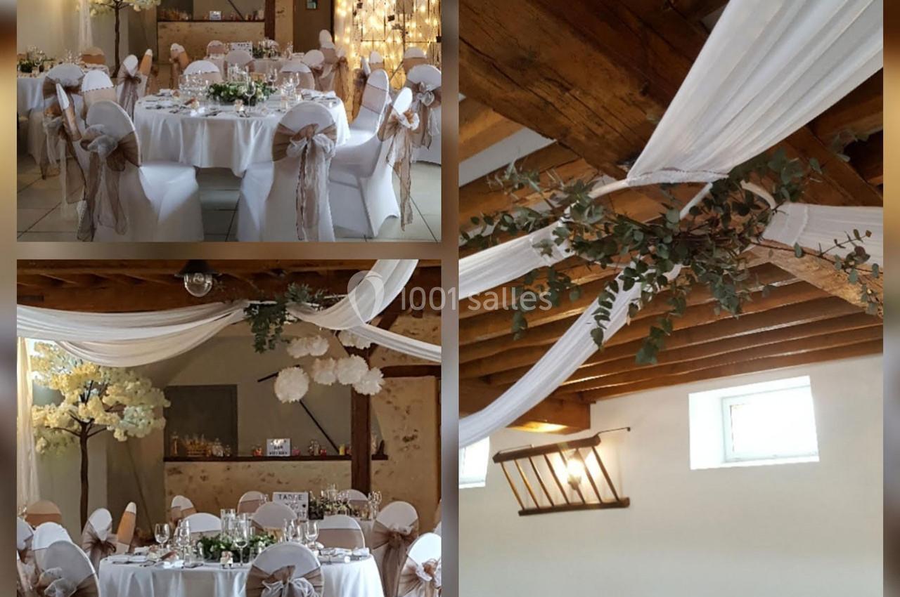 Salle de réception décorée avec des tables rondes, nappes blanches, chaises ornées de nœuds et drapés suspendus au plafond.