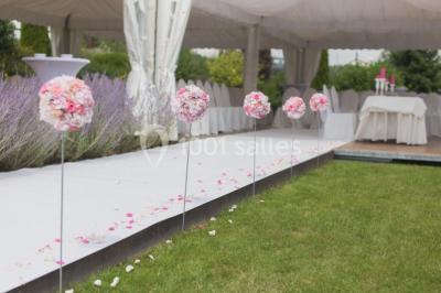 Un couple en tenue de mariage se tient la main dans un jardin baigné par une lumière douce au coucher du soleil.