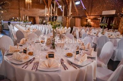 Un couple en tenue de mariage se tient la main dans un jardin baigné par une lumière douce au coucher du soleil.