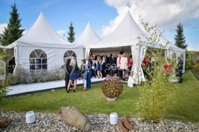 Un couple en tenue de mariage se tient la main dans un jardin baigné par une lumière douce au coucher du soleil.