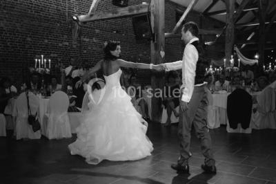 Un couple en tenue de mariage se tient la main dans un jardin baigné par une lumière douce au coucher du soleil.