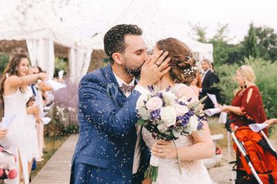 Un couple en tenue de mariage se tient la main dans un jardin baigné par une lumière douce au coucher du soleil.