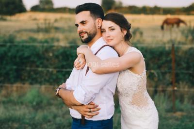 Un couple en tenue de mariage se tient la main dans un jardin baigné par une lumière douce au coucher du soleil.