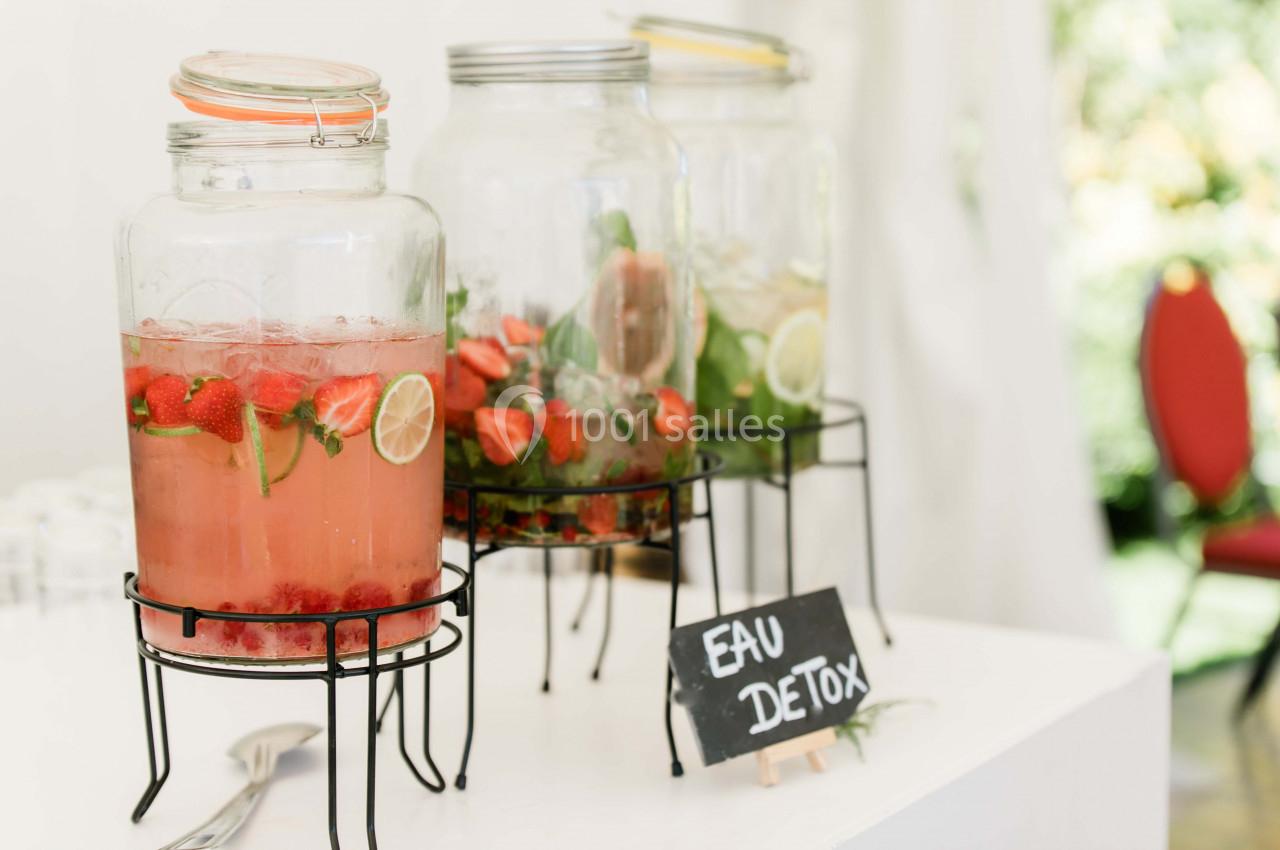 Trois jarres de verre contenant des eaux infusées aux fruits et herbes, avec une étiquette ’Eau Détox’.