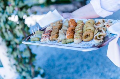 Un couple en tenue de mariage se tient la main dans un jardin baigné par une lumière douce au coucher du soleil.