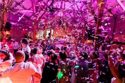 Un couple en tenue de mariage se tient la main dans un jardin baigné par une lumière douce au coucher du soleil.