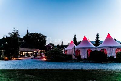 Un couple en tenue de mariage se tient la main dans un jardin baigné par une lumière douce au coucher du soleil.