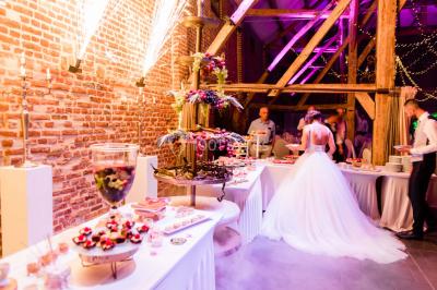 Un couple en tenue de mariage se tient la main dans un jardin baigné par une lumière douce au coucher du soleil.