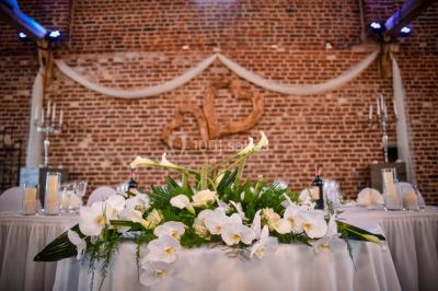 Un couple en tenue de mariage se tient la main dans un jardin baigné par une lumière douce au coucher du soleil.