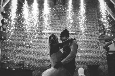 Un couple en tenue de mariage se tient la main dans un jardin baigné par une lumière douce au coucher du soleil.