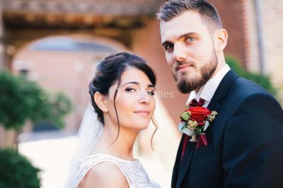 Un couple en tenue de mariage se tient la main dans un jardin baigné par une lumière douce au coucher du soleil.