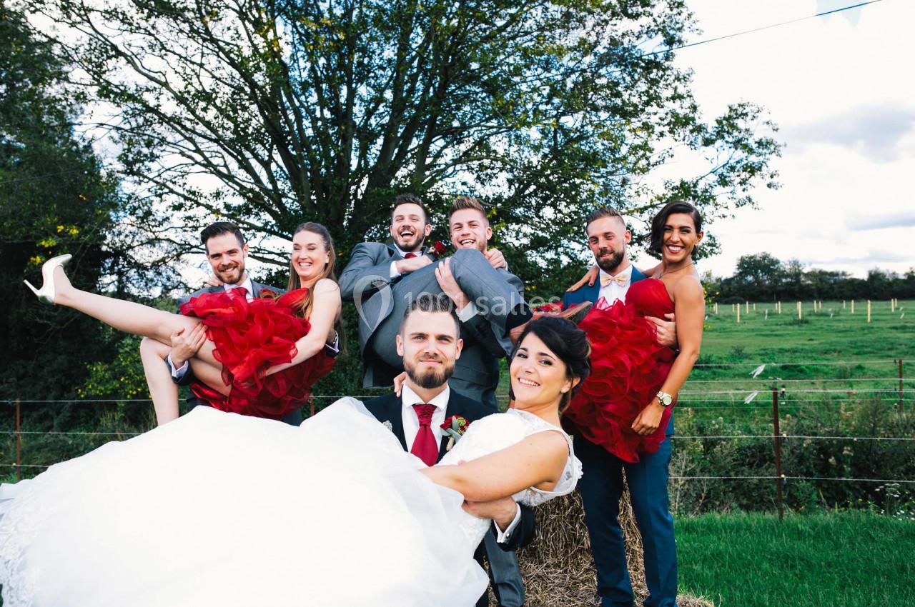 Un groupe de jeunes adultes en tenue de mariage pose joyeusement dans un cadre champêtre.