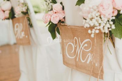 Un couple en tenue de mariage se tient la main dans un jardin baigné par une lumière douce au coucher du soleil.