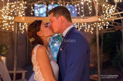 Un couple en tenue de mariage se tient la main dans un jardin baigné par une lumière douce au coucher du soleil.