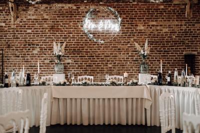 Un couple en tenue de mariage se tient la main dans un jardin baigné par une lumière douce au coucher du soleil.