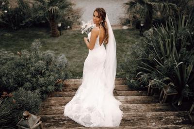 Un couple en tenue de mariage se tient la main dans un jardin baigné par une lumière douce au coucher du soleil.