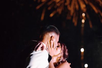 Un couple en tenue de mariage se tient la main dans un jardin baigné par une lumière douce au coucher du soleil.