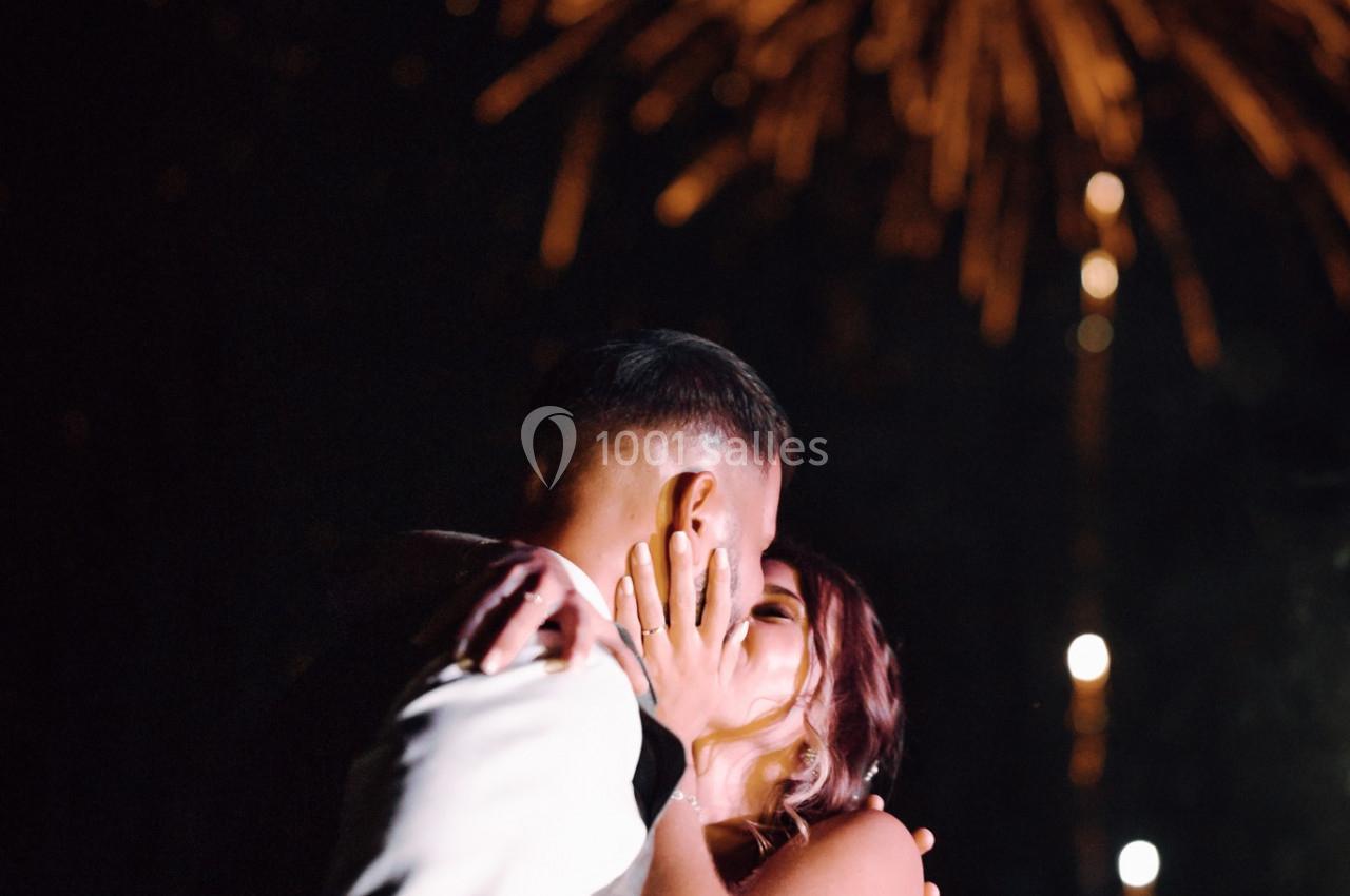 Un couple s'embrasse sous un ciel illuminé par des feux d'artifice.
