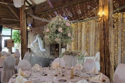 Un couple en tenue de mariage se tient la main dans un jardin baigné par une lumière douce au coucher du soleil.