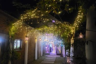 Un couple en tenue de mariage se tient la main dans un jardin baigné par une lumière douce au coucher du soleil.