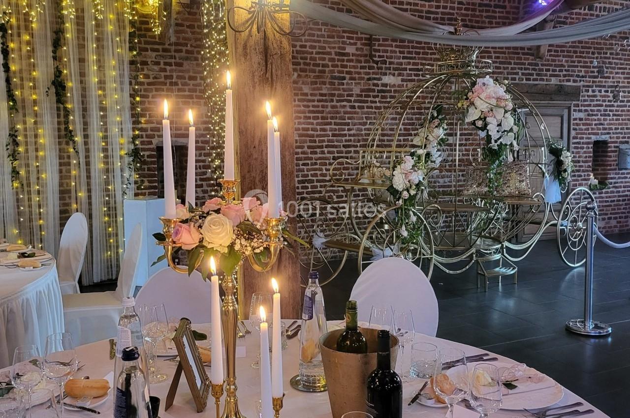 Salle de réception décorée avec des chandeliers, des fleurs et une calèche ornée de roses en arrière-plan.