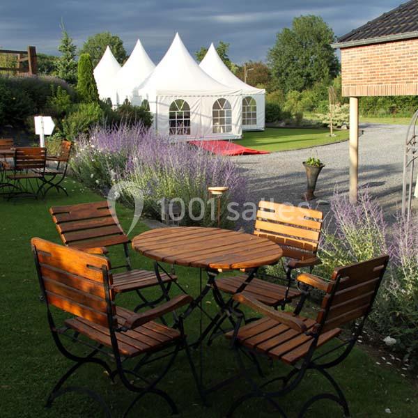 Mobilier de jardin en bois sur une pelouse, avec des tentes blanches et des lavandes en arrière-plan.