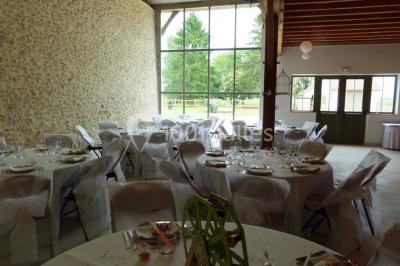 Salle lumineuse avec poutres apparentes, table décorée pour un candy bar sous une fenêtre de toit.
