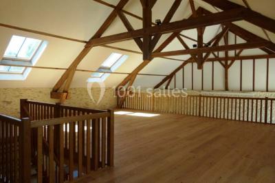 Salle lumineuse avec poutres apparentes, table décorée pour un candy bar sous une fenêtre de toit.