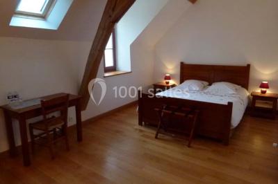 Salle lumineuse avec poutres apparentes, table décorée pour un candy bar sous une fenêtre de toit.