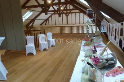 Salle lumineuse avec poutres apparentes, table décorée pour un candy bar sous une fenêtre de toit.