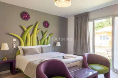 Miniature Location salle Ternand (Rhône) - Domaine des Pierres Dorées #20 Chambre lumineuse avec lit double, chaises colorées, table basse et accès à une salle de bain moderne.