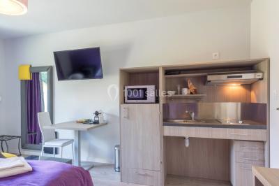 Miniature Location salle Ternand (Rhône) - Domaine des Pierres Dorées #23 Chambre lumineuse avec lit double, chaises colorées, table basse et accès à une salle de bain moderne.