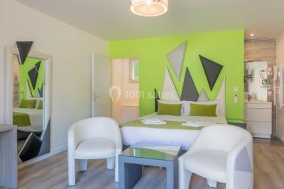 Miniature Location salle Ternand (Rhône) - Domaine des Pierres Dorées #28 Chambre lumineuse avec lit double, chaises colorées, table basse et accès à une salle de bain moderne.