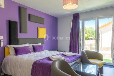 Miniature Location salle Ternand (Rhône) - Domaine des Pierres Dorées #29 Chambre lumineuse avec lit double, chaises colorées, table basse et accès à une salle de bain moderne.