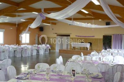 Bâtiment beige à un étage avec des fenêtres blanches, entouré d'une pelouse et d'arbustes, sous un ciel partiellement…