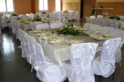 Bâtiment beige à un étage avec des fenêtres blanches, entouré d'une pelouse et d'arbustes, sous un ciel partiellement…