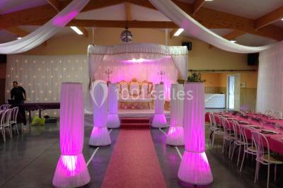 Bâtiment beige à un étage avec des fenêtres blanches, entouré d'une pelouse et d'arbustes, sous un ciel partiellement…