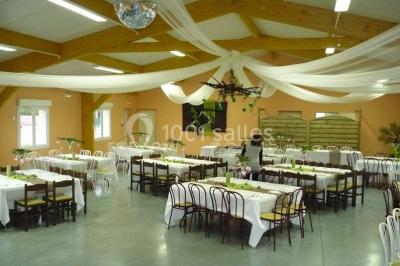 Bâtiment beige à un étage avec des fenêtres blanches, entouré d'une pelouse et d'arbustes, sous un ciel partiellement…