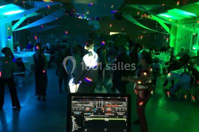 Bâtiment beige à un étage avec des fenêtres blanches, entouré d'une pelouse et d'arbustes, sous un ciel partiellement…