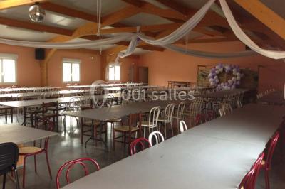 Bâtiment beige à un étage avec des fenêtres blanches, entouré d'une pelouse et d'arbustes, sous un ciel partiellement…