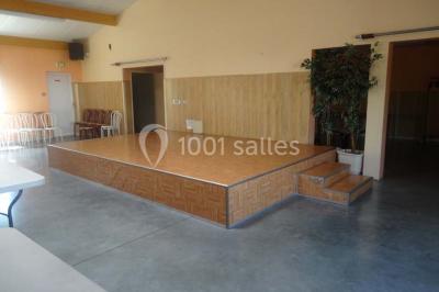 Bâtiment beige à un étage avec des fenêtres blanches, entouré d'une pelouse et d'arbustes, sous un ciel partiellement…