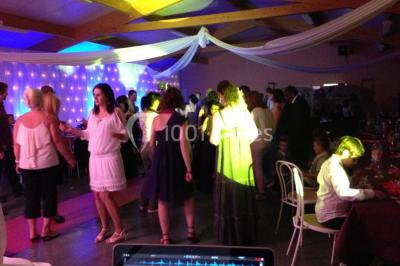 Bâtiment beige à un étage avec des fenêtres blanches, entouré d'une pelouse et d'arbustes, sous un ciel partiellement…