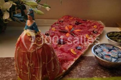 Bâtiment beige à un étage avec des fenêtres blanches, entouré d'une pelouse et d'arbustes, sous un ciel partiellement…